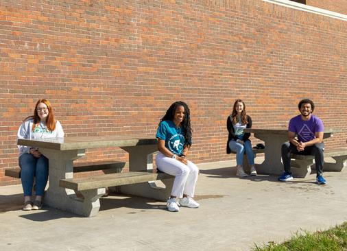 四个学生领袖坐在外面的混凝土野餐桌旁